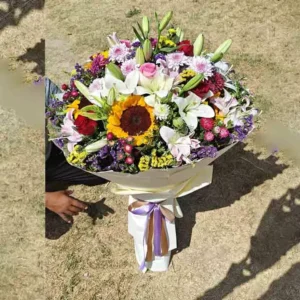 Large, round mixed flower bouquet featuring lilies, sunflowers, roses, and various vibrant fillers